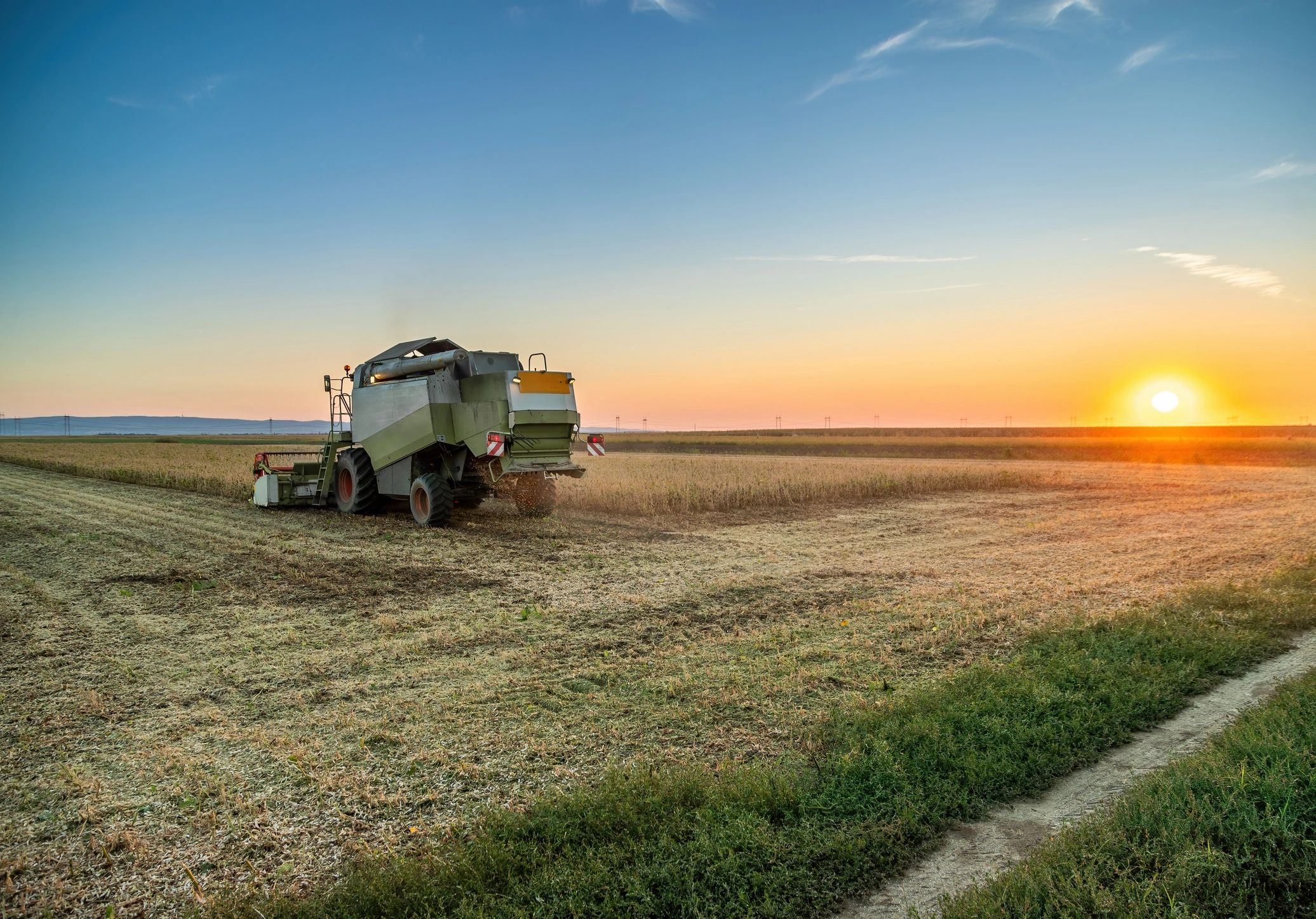 Combine harvester working in a field at sunset